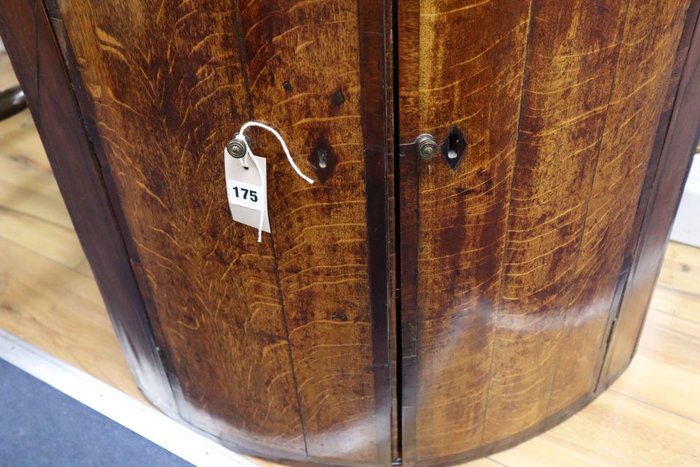A George III oak bow-fronted hanging corner cupboard, mahogany-banded, width 64cm